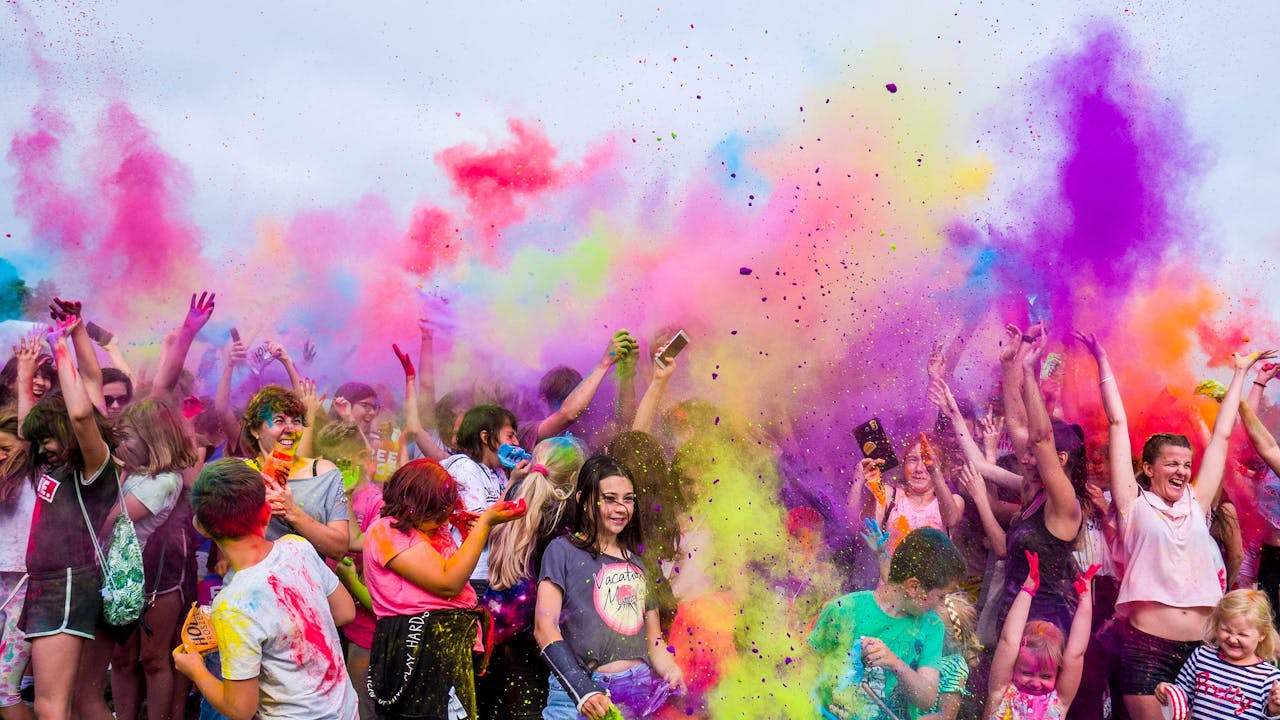 Home A joyful crowd covered in vivid colors celebrates a festival outdoors with flying powder.